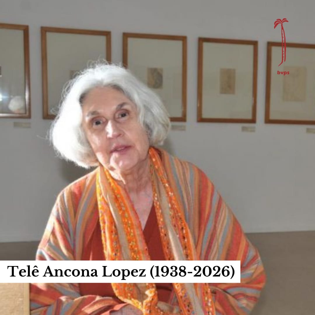 Professora Telê Ancona Lopez em galeria com manuscritos emoldurados ao fundo